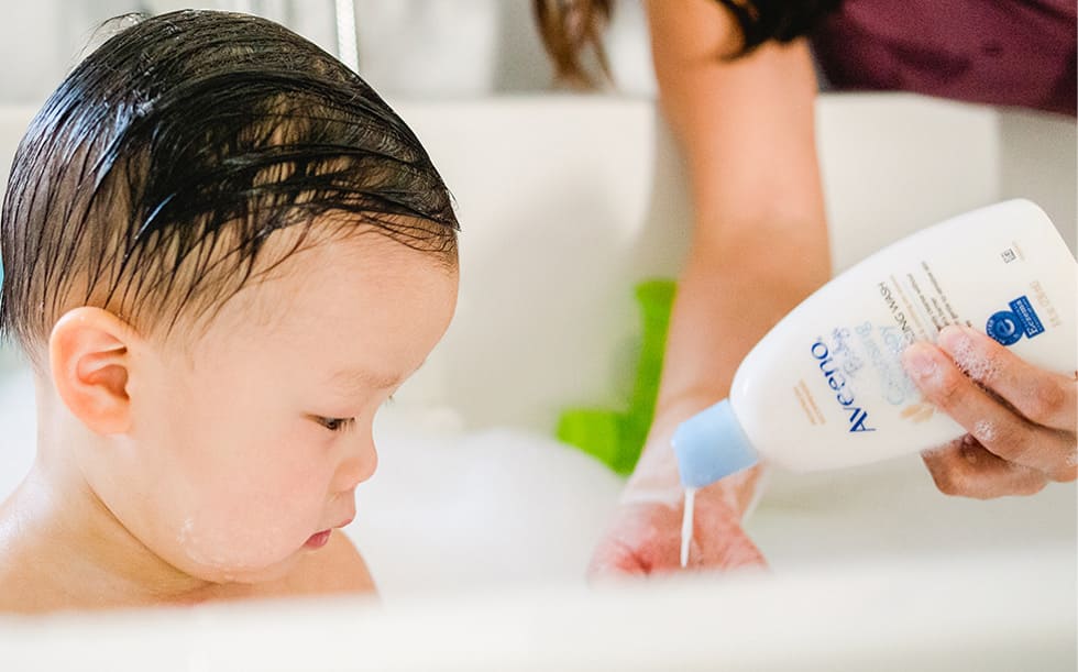Bébé prenant un bain moussant contenant un produit AVEENO® Baby Soin de l’eczéma